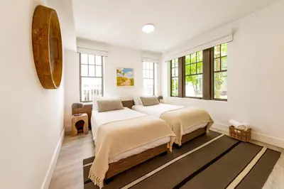 two beds in a room with white walls and windows at Casa Sofi in Miami Beach