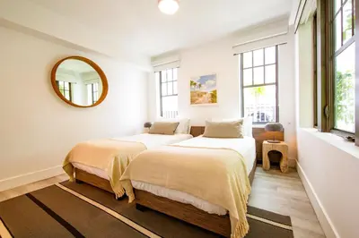 two beds in a white room with a mirror at Casa Sofi in Miami Beach