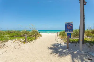 a sign on a sandy beach next to the ocean at Girasole Apartments in Miami Beach