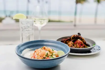 a table with a bowl of food and a glass of wine at Hotel Maren Fort Lauderdale Beach, Curio Collection By Hilton in Fort Lauderdale