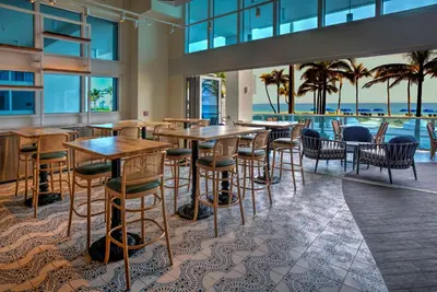 a restaurant with tables and chairs and a view of the ocean at Hotel Maren Fort Lauderdale Beach, Curio Collection By Hilton in Fort Lauderdale