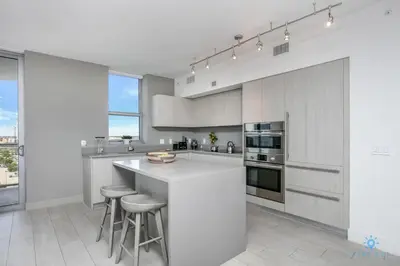 a kitchen with white cabinets and bar stools at Corner Balcony - Enjoy 360 Views- Near Beach- Pool in Hollywood