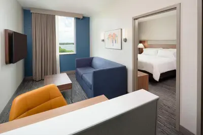 a hotel room with a bed and a blue chair at Holiday Inn Express Miami Airport-Blue Lagoon Area by IHG in Miami