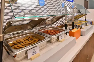 a buffet line with trays of food on a counter at Holiday Inn Express Miami Airport-Blue Lagoon Area by IHG in Miami