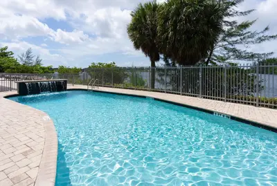 a large swimming pool with a fence and trees at Holiday Inn Express Miami Airport-Blue Lagoon Area by IHG in Miami