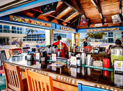 a restaurant with a bar with people in the background at Castle 1733 Ocean view studio with direct beach access, pool, tennis & free parking in Miami Beach