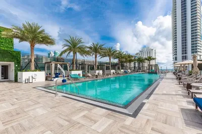 a swimming pool with palm trees and a building at Family 3 bedroom Hyde Beach House Miami 22th floor in Hallandale Beach