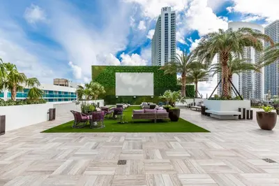 a rooftop patio with furniture and a screen on a building at Family 3 bedroom Hyde Beach House Miami 22th floor in Hallandale Beach