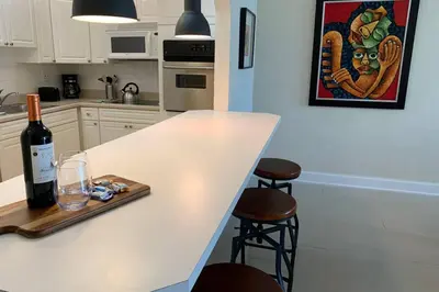 a kitchen counter with a bottle of wine and two stools at Beautiful Apartment Steps Away from the Beach in Miami Beach