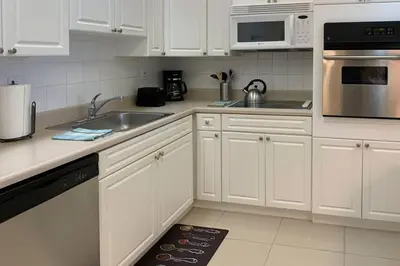 a kitchen with white cabinets and a sink and microwave at Beautiful Apartment Steps Away from the Beach in Miami Beach