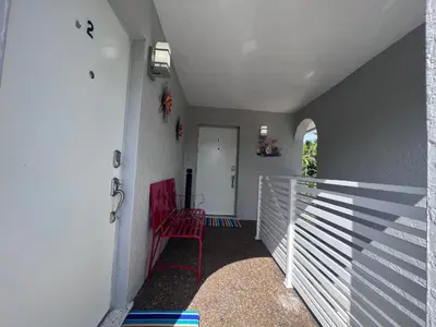 a hallway with a white fence and a red chair at Stylish Studio Apartment By Miami International Airport in Miami