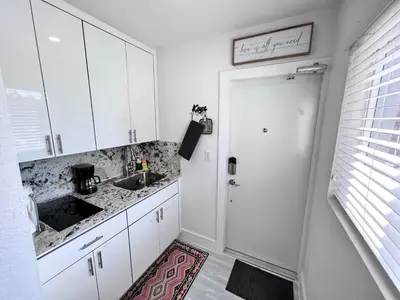 a kitchen with white cabinets and a sink and a door at Stylish Studio Apartment By Miami International Airport in Miami