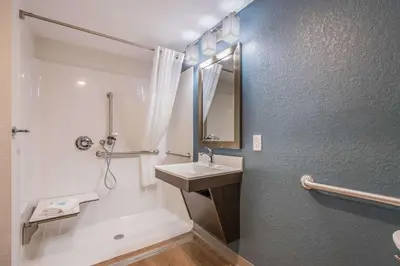 a bathroom with a sink and a shower with a mirror at WoodSpring Suites Doral Miami Airport in Miami