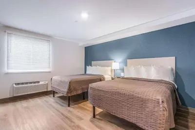 two beds in a small room with blue walls at WoodSpring Suites Doral Miami Airport in Miami