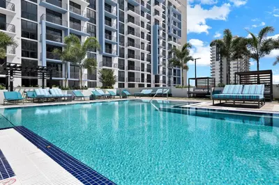 a swimming pool with blue chairs and a building at Provident Grand Luxury Short-Term Residences in Miami