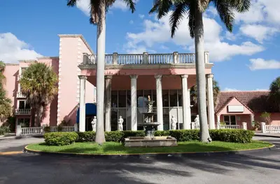 a pink building with palm trees and a fountain at Miami Gardens Inn & Suites in Miami