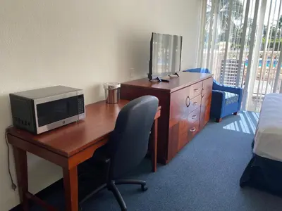 a room with a desk with a microwave and a television at Miami Gardens Inn & Suites in Miami