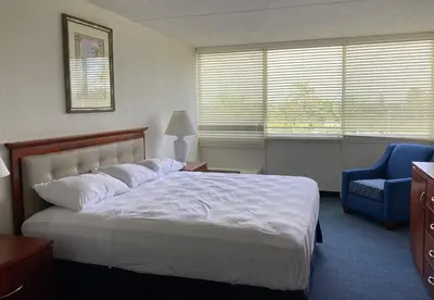 a bedroom with a white bed and a blue chair at Miami Gardens Inn & Suites in Miami