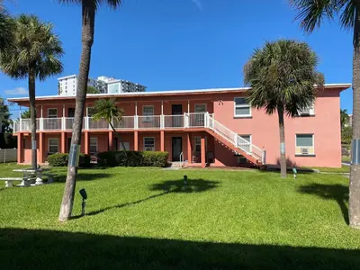 a large orange building with palm trees in the yard at Rolo Beach Hotel in Fort Lauderdale