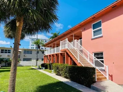 a pink building with a staircase next to a palm tree at Rolo Beach Hotel in Fort Lauderdale