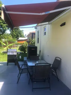 a patio with a table and chairs and an umbrella at Your House in Miami in Miami