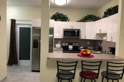 a kitchen with a counter with chairs and a bowl of fruit at Your House in Miami in Miami