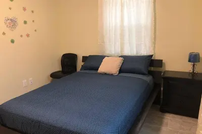 a bedroom with a bed with blue sheets and a window at Your House in Miami in Miami