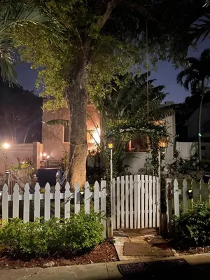 a white picket fence in front of a tree at Ne Miami Cottage in Miami