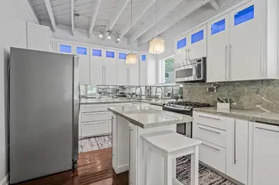 a large kitchen with white cabinets and a refrigerator at villa venezia bb in Miami Beach