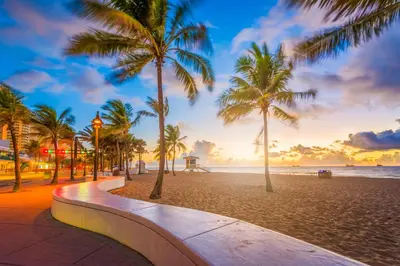 a beach with palm trees and the ocean at sunset at Fountain condo 2 story Pool BBQ Balcony in Miami Beach