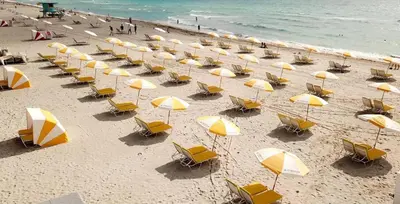 a bunch of chairs and umbrellas on a beach at Nine20 Collins Apartments by Lowkl in Miami Beach