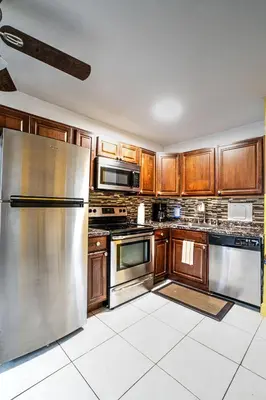 a kitchen with wooden cabinets and stainless steel appliances at Little Paris by the ocean self check in in Fort Lauderdale