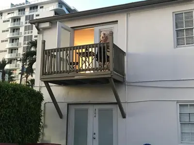 a woman looking out from a balcony of a building at Little Paris by the ocean self check in in Fort Lauderdale