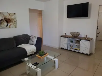 a living room with a couch and a tv on a wall at Sophisticated Dania Beach Suites Near the Beach in Dania Beach