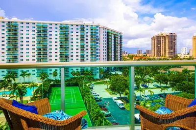 a balcony of a resort with chairs and a tennis court at Sunny Isles Ocean Reserve Condo Apartments - 1BR #812 in Miami Beach