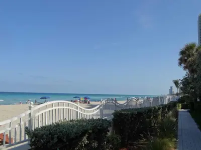 a beach with a white fence and the ocean at Apartamento en la Playa The Tides in Hollywood