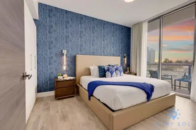 a bedroom with a bed with a blue accent wall at EXCLUSIVE APARTMENT - Rooftop POOL- Beachfront in Hollywood