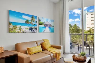 a living room with a couch and a large window at Best Stay - Rooftop Pool & Hot Tub - Hollywood Beach in Hollywood