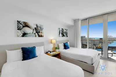 two beds in a hotel room with a balcony at Amenities BALCONY w Stunning Views-Beachfront in Hallandale Beach