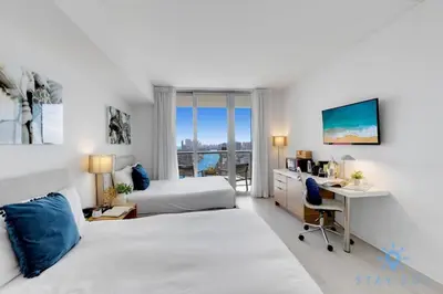 a bedroom with a bed and a desk with a computer at Amenities BALCONY w Stunning Views-Beachfront in Hallandale Beach