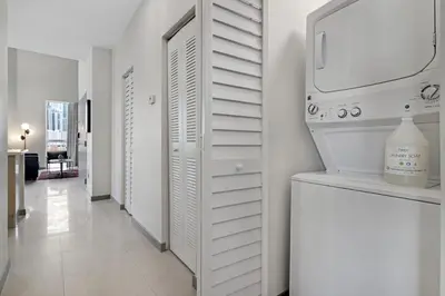 a kitchen with white cabinets and a washer and dryer at Roami at Habitat Brickell in Miami