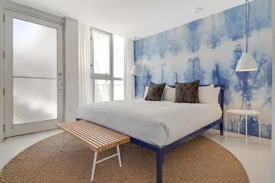 a bedroom with a large bed with a blue wall at Roami at 250 Collins in Miami Beach