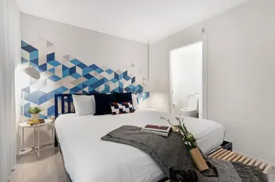 a bedroom with a large white bed with a blue accent wall at Roami at 250 Collins in Miami Beach