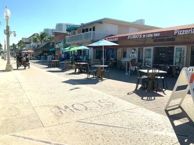 a street with tables and umbrellas on a sidewalk at Hollywood Beach Apartments - Walk to the Beach in Hollywood