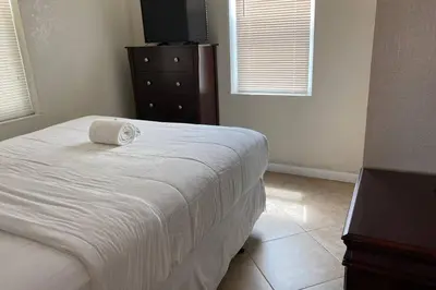 a bedroom with a bed and a dresser and two windows at Hollywood Beach Apartments - Walk to the Beach in Hollywood