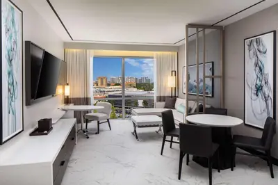 a hotel room with tables and chairs and a large window at Hilton Miami Aventura in Aventura