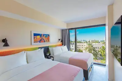 a hotel room with two beds and a window at Moxy Miami South Beach in Miami Beach