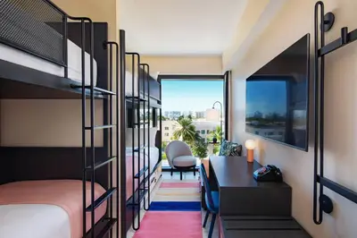 a room with bunk beds and a desk and a table at Moxy Miami South Beach in Miami Beach