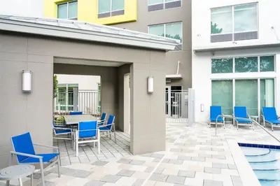 a patio with blue chairs and a table and a pool at Holiday Inn Express Doral Miami by IHG in Doral