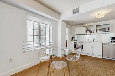a white kitchen with a glass table and chairs at The Carlyle 3G in Miami Beach